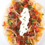 Pulled Pork Nachos - Fall off the bone pulled pork on top of tortillas with shredded cheese, then loaded with diced tomatoes, salsa, sour cream, and cilantro!