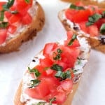 Tomato and Basil Crostini with Whipped Feta - Crunchy crostini with zesty, tangy, creamy whipped feta, then topped with diced tomatoes and garnished with fresh basil.
