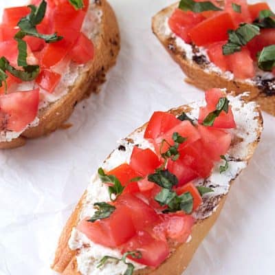 Tomato and Basil Crostini with Whipped Feta - Crunchy crostini with zesty, tangy, creamy whipped feta, then topped with diced tomatoes and garnished with fresh basil.