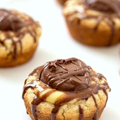 Boston Cream Sugar Cookie Cups - So easy anyone will be able to bake these! Sugar cookie cups baking with vanilla pudding in the center and topped with a dollop of chocolate fudge frosting. So good.