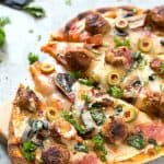 Easy Spicy Italian Sausage Grilled Flatbread Pizza - Crispy and Grilled naan flatbread layered with pizza sauce, shredded mozzarella cheese, hot Italian sausage, salami, manzanilla olives, mushrooms, and fresh basil! The perfect summer appetizer or main dish!