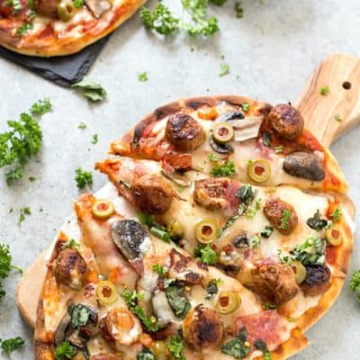 Easy Spicy Italian Sausage Grilled Flatbread Pizza - Crispy and Grilled naan flatbread layered with pizza sauce, shredded mozzarella cheese, hot Italian sausage, salami, manzanilla olives, mushrooms, and fresh basil! The perfect summer appetizer or main dish!