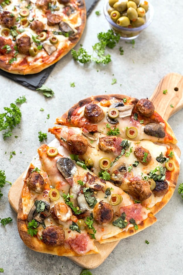 Easy Spicy Italian Sausage Grilled Flatbread Pizza - Crispy and Grilled naan flatbread layered with pizza sauce, shredded mozzarella cheese, hot Italian sausage, salami, manzanilla olives, mushrooms, and fresh basil! The perfect summer appetizer or main dish!