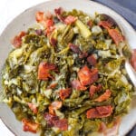 Looking down on a small plate of cooked collar greens with bacon