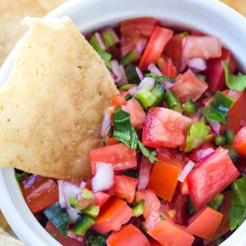 Looking down at a bowl of tomato salsa with a chip