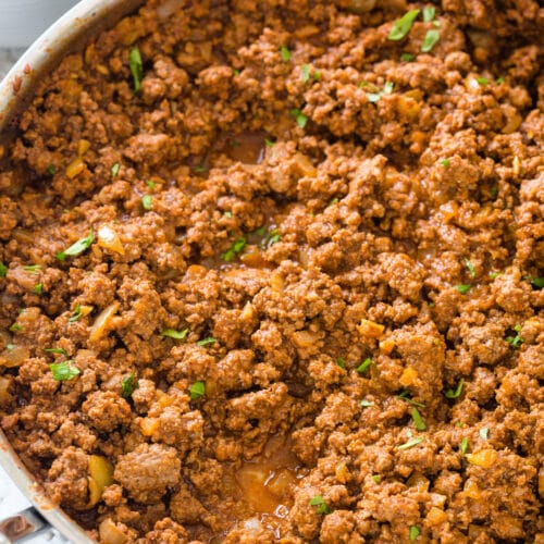 Looking down at taco meat in a stainless steel pan with parsley