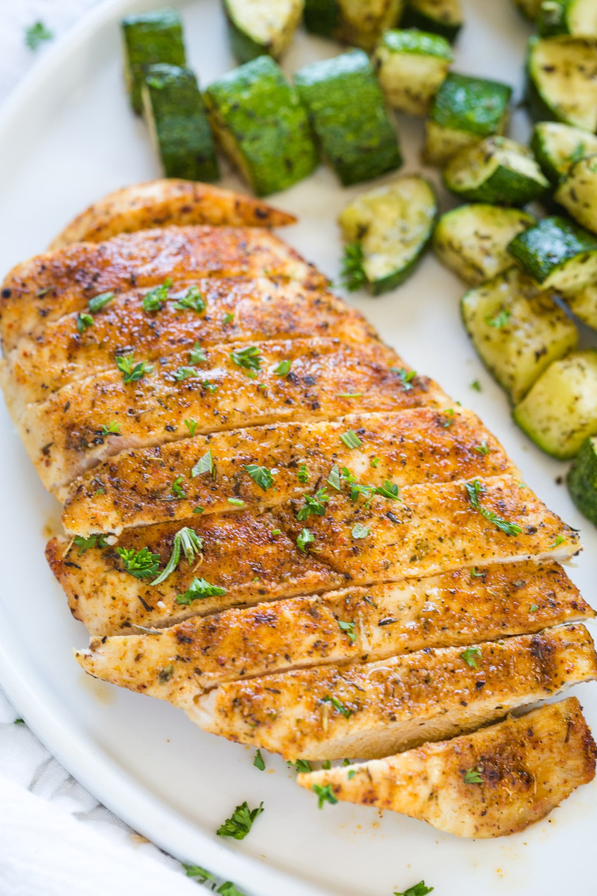 looking at a cooked chicken breast on a plate with diced and cooked zucchini