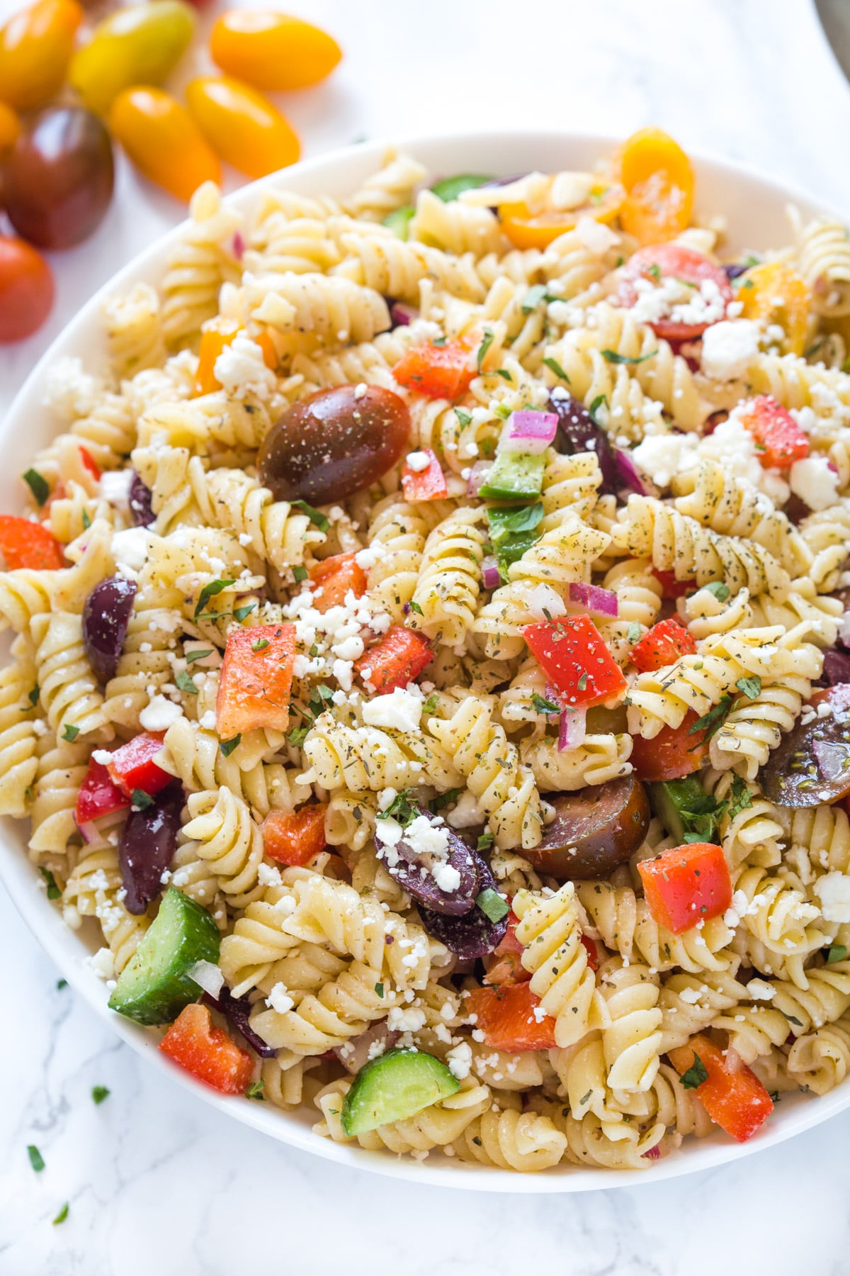 Close up of Greek pasta salad in a bowl bowl on a marble surface