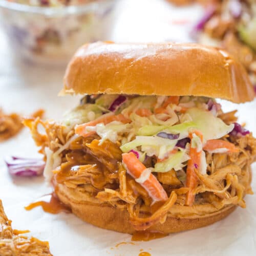 shredded bbq chicken with bbq sauce on top of a bun with coleslaw