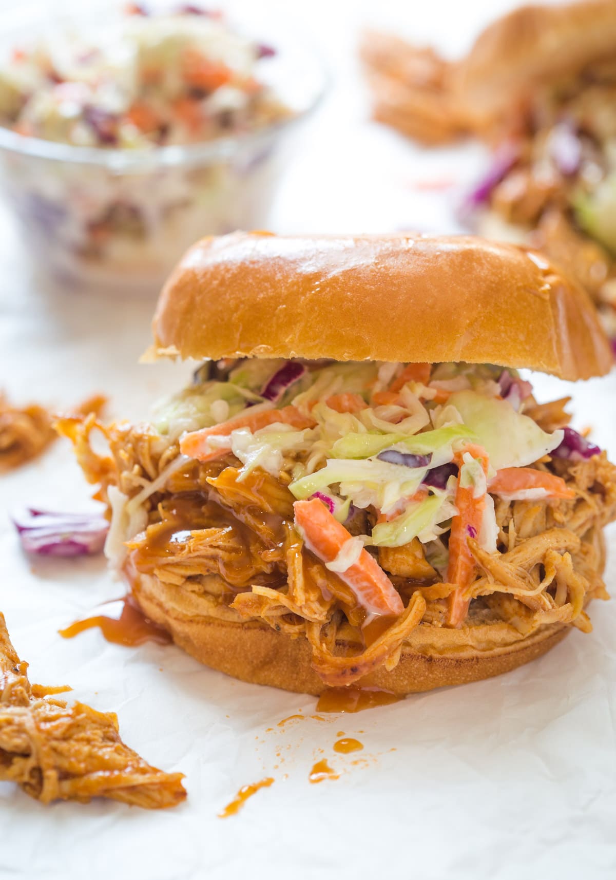 shredded bbq chicken with bbq sauce on top of a bun with coleslaw